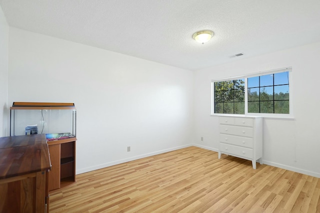 bedroom with a textured ceiling and light wood-type flooring