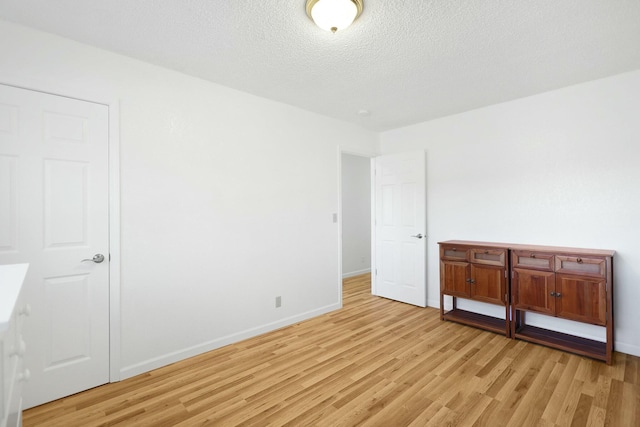 spare room featuring a textured ceiling and light hardwood / wood-style flooring