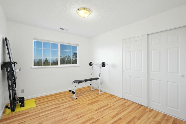 exercise room with hardwood / wood-style floors and a textured ceiling