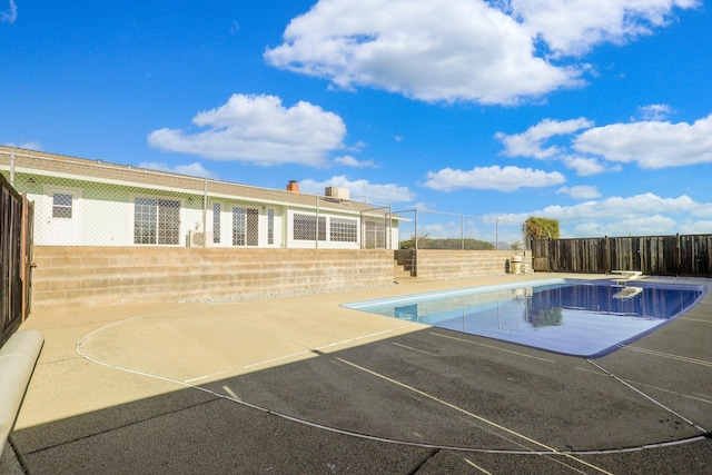 view of swimming pool featuring a diving board and a patio area