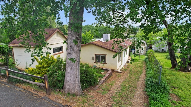 view of property exterior with fence, a lawn, and stucco siding