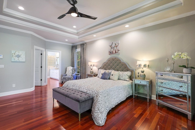 bedroom with ceiling fan, ensuite bath, a raised ceiling, crown molding, and dark wood-type flooring