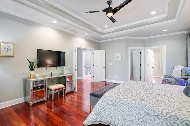 bedroom featuring ceiling fan, a tray ceiling, dark wood-type flooring, connected bathroom, and ornamental molding