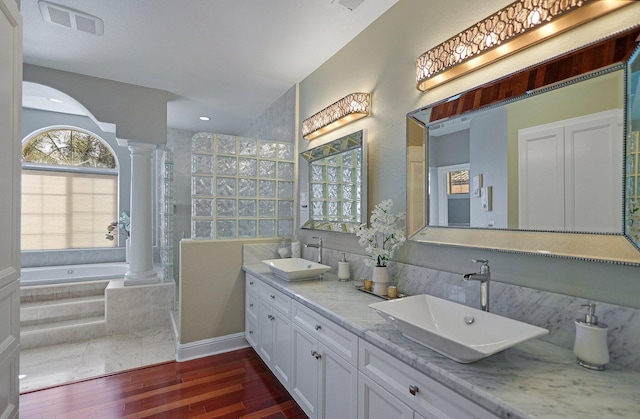 bathroom featuring a relaxing tiled tub, wood-type flooring, vanity, and decorative columns