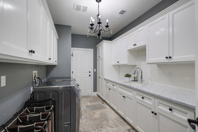 laundry area featuring cabinets, washer and dryer, a chandelier, and sink