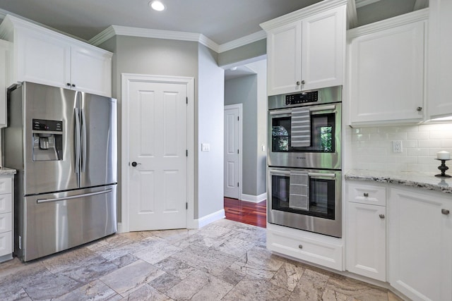 kitchen featuring light stone countertops, white cabinets, appliances with stainless steel finishes, and ornamental molding