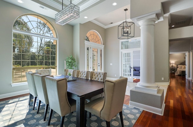 dining area with dark wood-type flooring, a wealth of natural light, ornamental molding, and an inviting chandelier