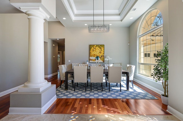 dining room featuring a raised ceiling, wood-type flooring, a notable chandelier, and ornamental molding