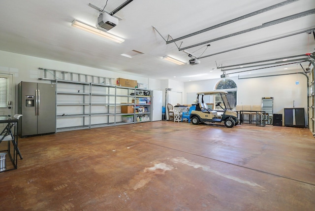 garage featuring stainless steel fridge and a garage door opener