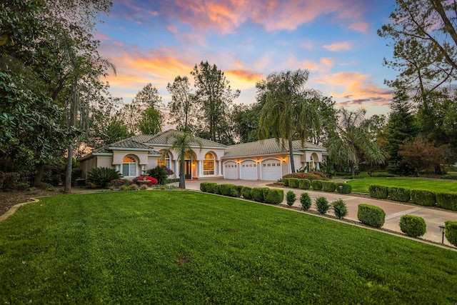 mediterranean / spanish home featuring a garage and a lawn