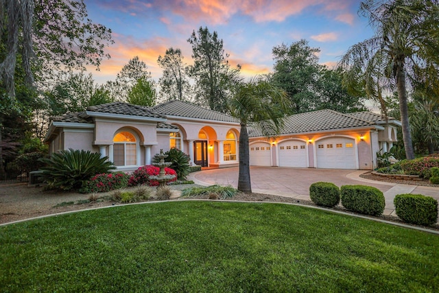 mediterranean / spanish-style house featuring a yard and a garage