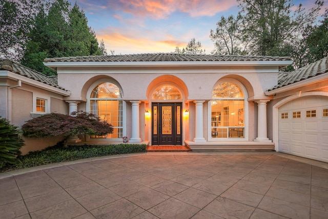 exterior entry at dusk featuring a garage