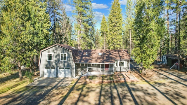 view of front of home with a garage, a porch, and a shed