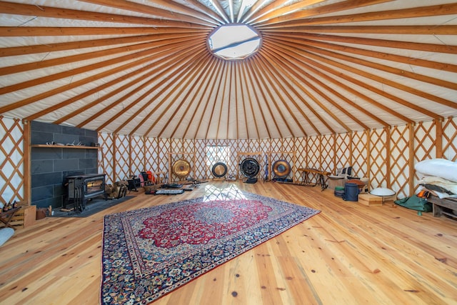 unfurnished living room with vaulted ceiling, a wood stove, and hardwood / wood-style floors