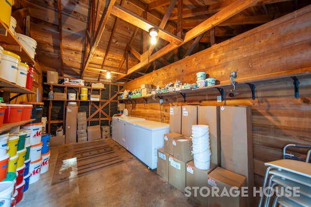 basement featuring fridge and wood walls