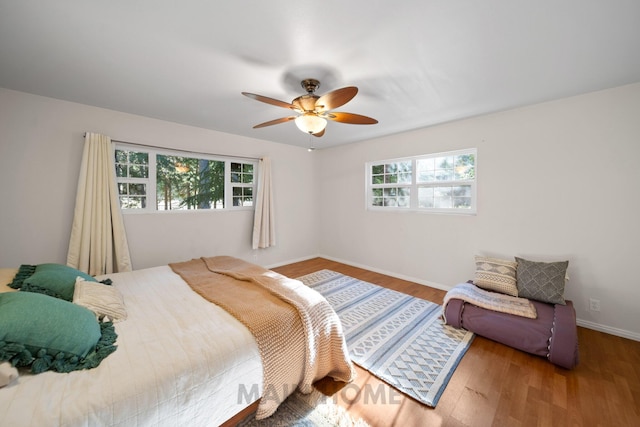 bedroom with hardwood / wood-style flooring, ceiling fan, and multiple windows