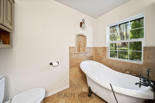 bathroom featuring a healthy amount of sunlight, toilet, tile walls, and a tub