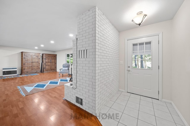 entryway with light wood-type flooring, heating unit, and a wealth of natural light