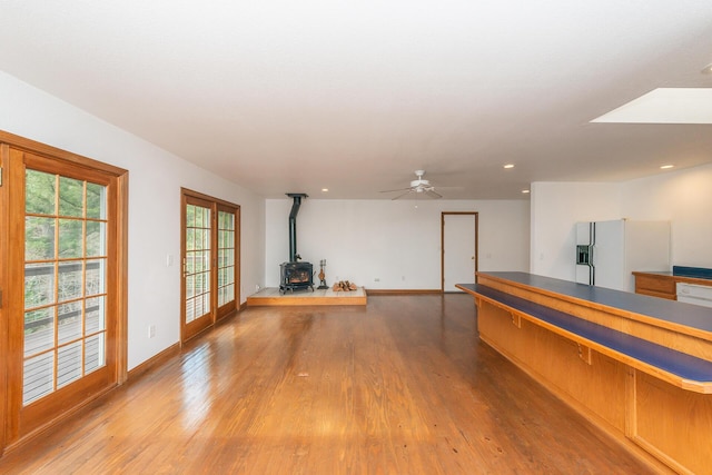 interior space featuring french doors, ceiling fan, a wood stove, and hardwood / wood-style floors