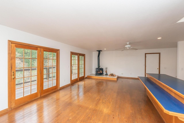 interior space featuring ceiling fan, french doors, a wood stove, and hardwood / wood-style flooring