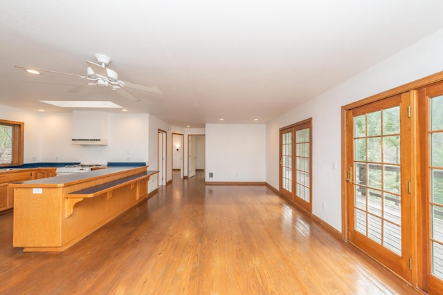 interior space featuring ceiling fan, light hardwood / wood-style floors, a breakfast bar, stove, and french doors