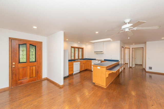 kitchen featuring white appliances, dark wood-type flooring, sink, kitchen peninsula, and ceiling fan