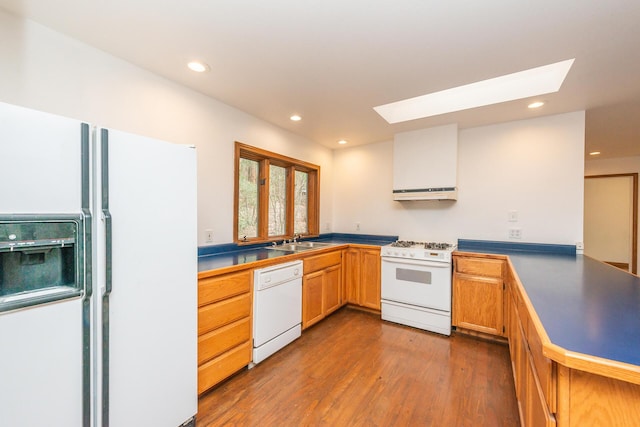 kitchen featuring white appliances, wood-type flooring, a skylight, sink, and kitchen peninsula