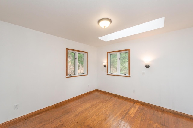 empty room featuring a skylight and wood-type flooring