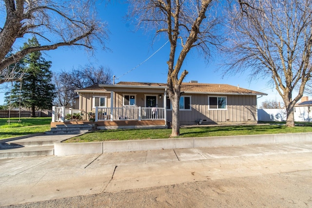 ranch-style home featuring covered porch, fence, board and batten siding, and a front yard