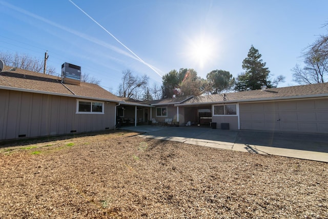 back of property with a garage and central air condition unit