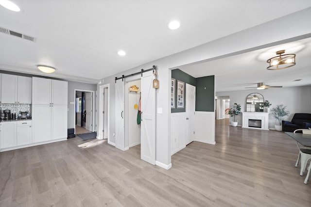 living room featuring light hardwood / wood-style flooring, a barn door, ceiling fan, and plenty of natural light