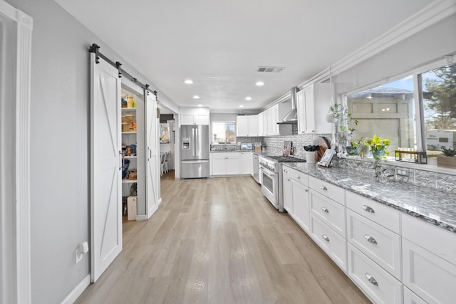 kitchen featuring a barn door, visible vents, white cabinets, appliances with stainless steel finishes, and light stone countertops