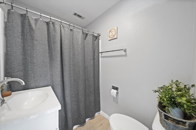 bathroom with wood-type flooring, vanity, and toilet