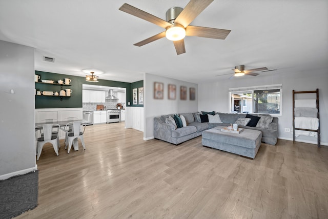 living room with light hardwood / wood-style flooring and ceiling fan