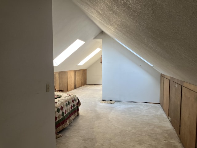 additional living space featuring light carpet, a textured ceiling, and vaulted ceiling with skylight