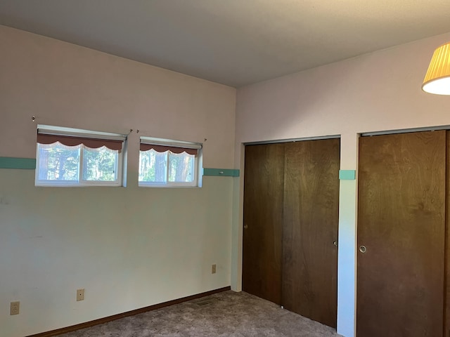 unfurnished bedroom with multiple closets and carpet flooring