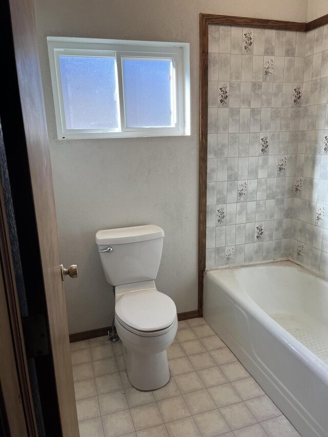 bathroom with a tub to relax in, toilet, and tile patterned flooring