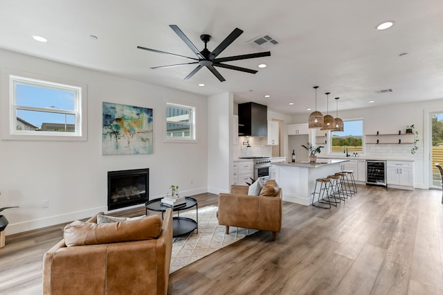 living room with ceiling fan, sink, wine cooler, and light hardwood / wood-style floors