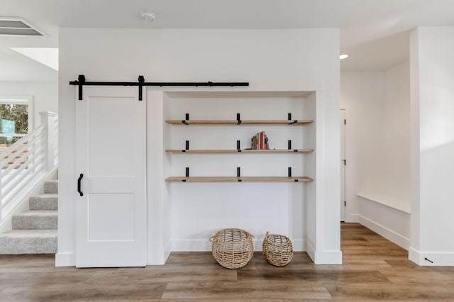 mudroom with a barn door and light hardwood / wood-style floors