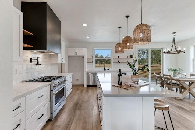 kitchen featuring sink, stainless steel appliances, light hardwood / wood-style floors, white cabinets, and decorative light fixtures