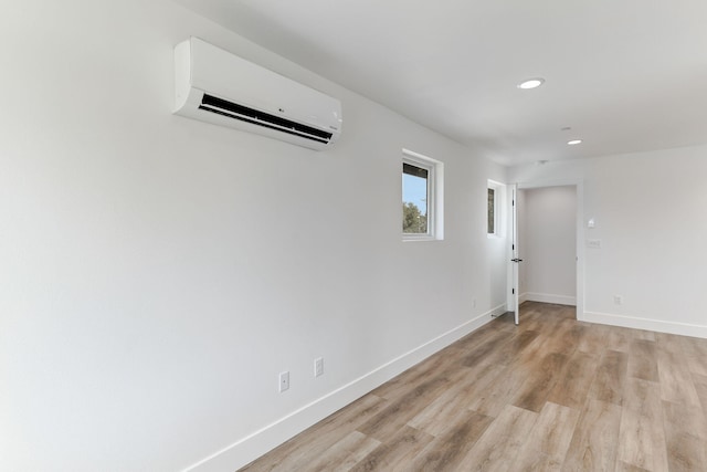 empty room with a wall unit AC and light wood-type flooring