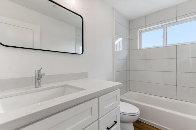 full bathroom with vanity, tiled shower / bath, hardwood / wood-style flooring, and toilet