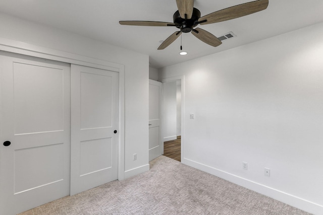 unfurnished bedroom with ceiling fan, light colored carpet, and a closet