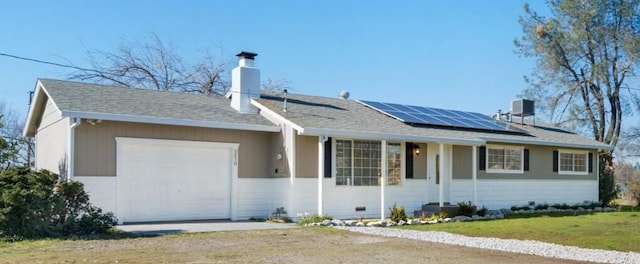 single story home featuring a garage, a front lawn, and solar panels