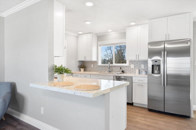 kitchen featuring sink, white cabinetry, stainless steel appliances, light stone countertops, and kitchen peninsula