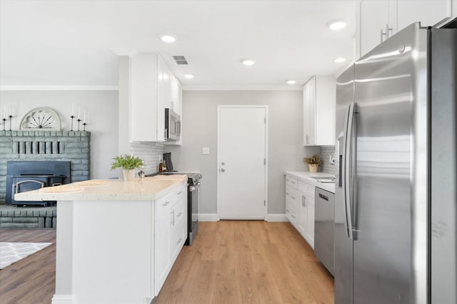 kitchen featuring white cabinetry, stainless steel appliances, light hardwood / wood-style flooring, and backsplash