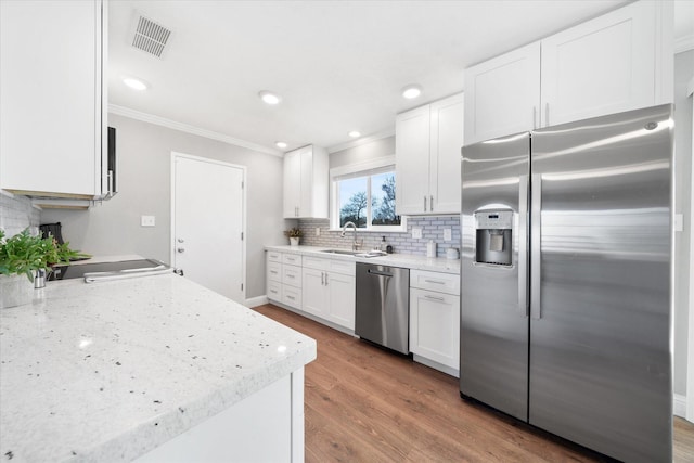 kitchen with sink, crown molding, appliances with stainless steel finishes, hardwood / wood-style floors, and white cabinets