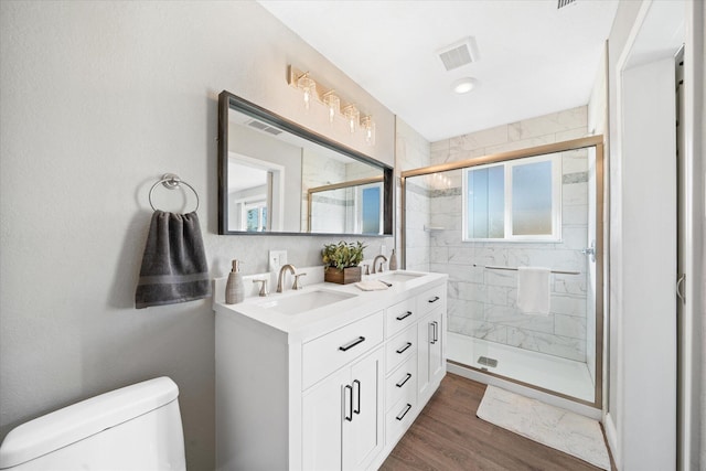 bathroom featuring a shower with door, wood-type flooring, vanity, and toilet