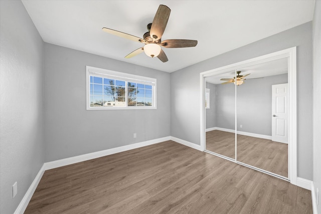 unfurnished bedroom with wood-type flooring, ceiling fan, and a closet