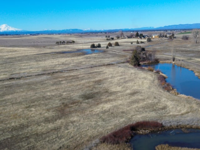 drone / aerial view with a water and mountain view and a rural view